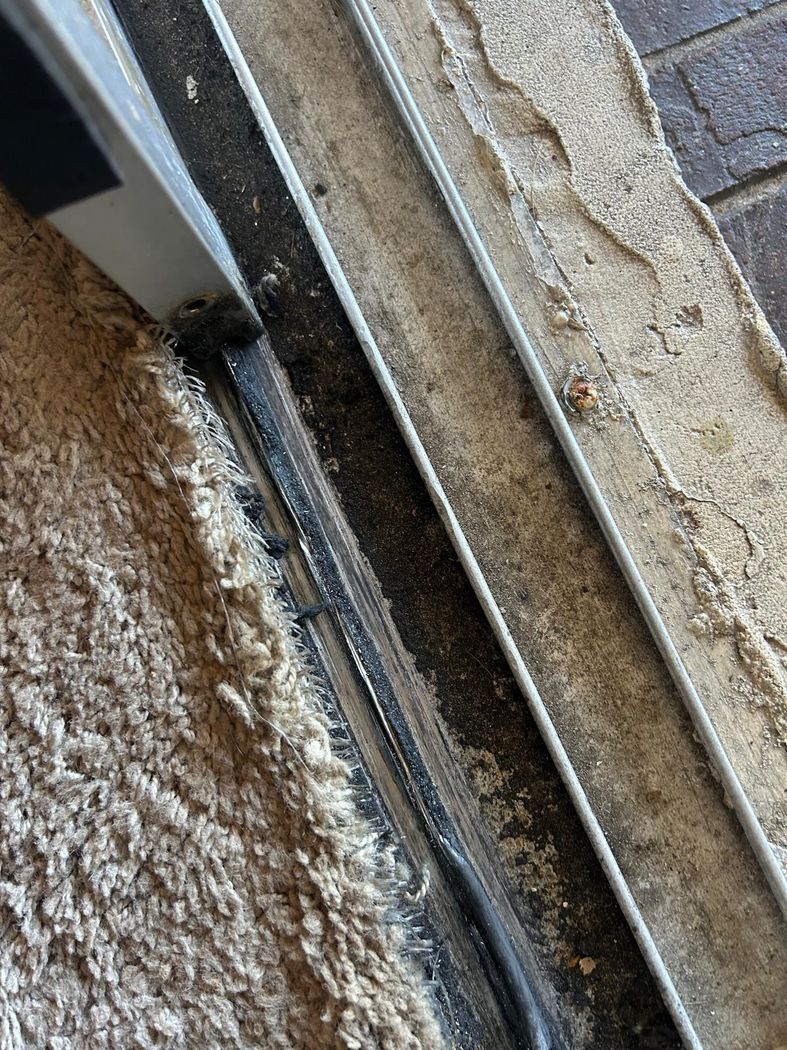 A sliding door track and weatherstripping being maintained